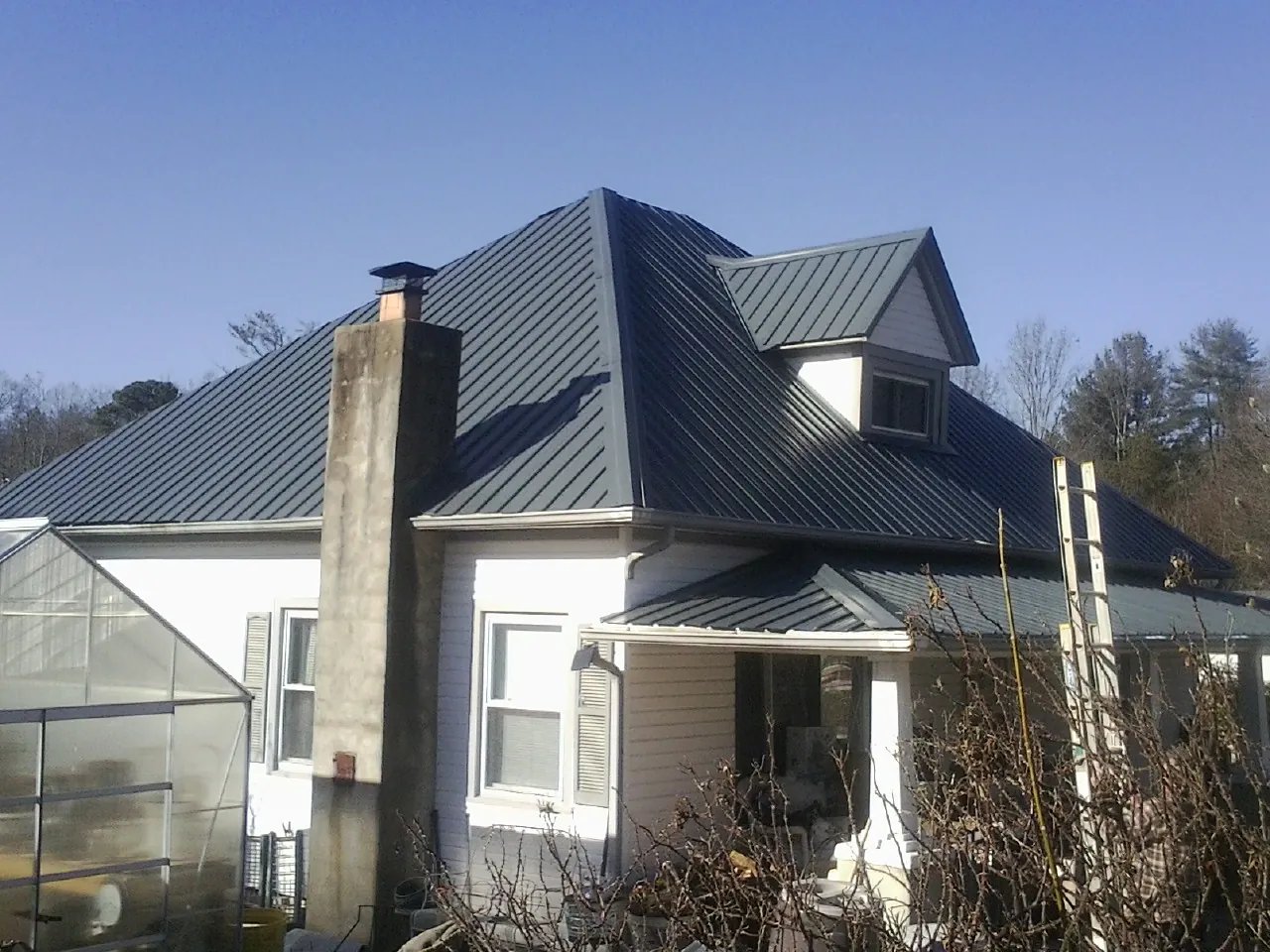 Dark blue standing seam metal roof on a white farmhouse with dormer — Slate & Tile Roof Repair by Roofing Brothers in Wyncote