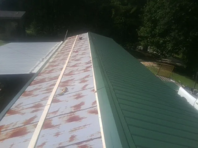 Old rusted panels beside newly installed green metal roofing — Wind Damage Roof Repair by Roofing Brothers in Wyncote