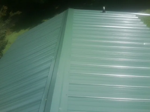New green metal panels meeting at the ridge of a roof — Flat Roof Repair work by our crew in Wyncote
