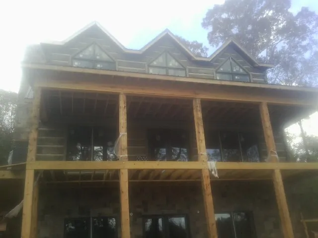 Dormers and porch framing on a large log home under construction — Roof Coating work by our crew in Wyncote