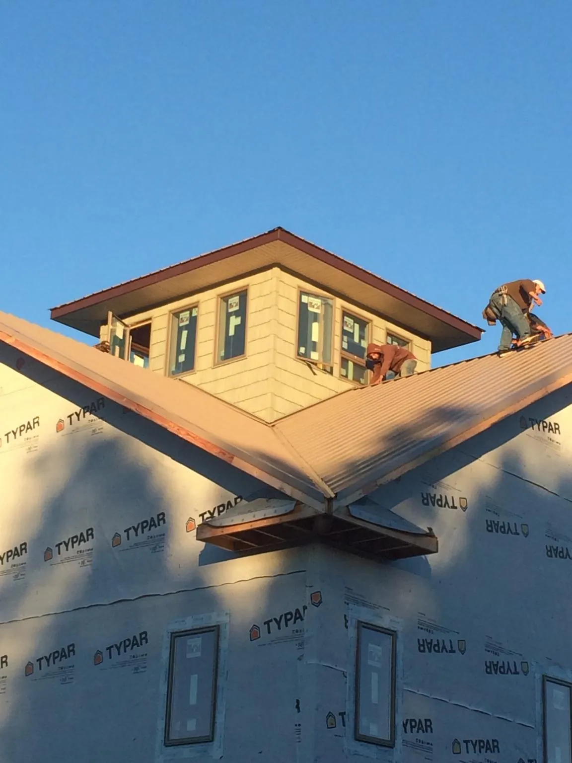 Roofers working around a rooftop cupola on a new metal roof at sunset — Roof Waterproofing in Wyncote by Roofing Brothers